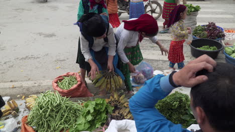Vietnamese-women-buying-groceries-in-a-sidewalk-street-stall-market,-Vietnam