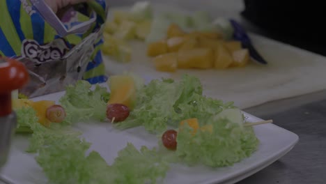 Plate-of-fruit-kebabs-being-prepared-on-a-bed-of-lettuce