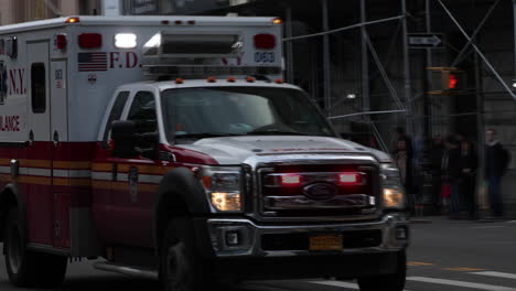 Slow-motion-shot-of-ambulance-with-flashing-lights-driving-on-a-street-of-Manhattan-in-New-York