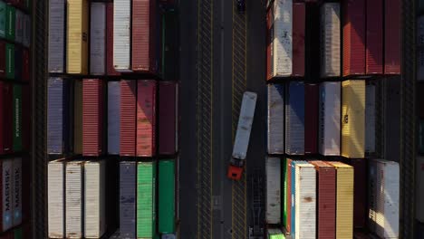 Aerial-View-Of-Unloaded-Truck-Passing-Between-Rows-Of-Colored-Shipping-Containers-At-The-Port