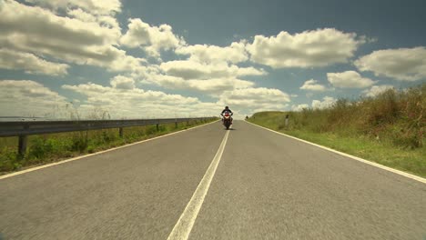 Man-riding-a-sporty-motorbike-to-a-beautiful-country-estate-in-Tuscany-in-bright-sunshine-and-landscape