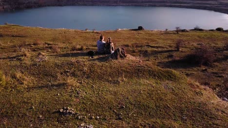 Una-Pareja-Sentada-En-El-Borde-De-Una-Roca-Mirando-El-Atardecer