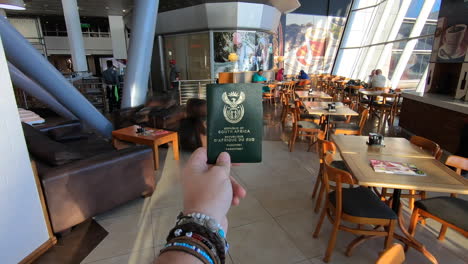 Male-hand-holding-a-South-African-passport-moving-through-an-empty-airport