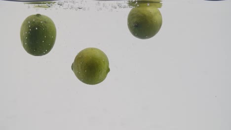 Whole-limes-splashing-in-water