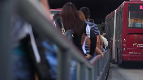 Cola-De-Pasajeros-En-La-Estación-De-Autobuses-Filmada-Desde-Atrás-A-La-Altura-De-La-Cadera-A-Lo-Largo-De-Una-Barrera-Metálica