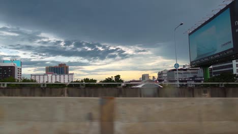 Toma-Tomada-Desde-Un-Automóvil-Que-Se-Mueve-A-Través-De-Un-Puente-En-Un-Día-Nublado-En-Bangkok-Durante-La-Noche.