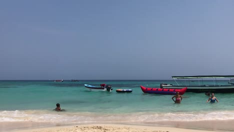 Kind-Spielt-Im-Meer-Mit-Seiner-Familie-Neben-Booten,-Die-Kurz-Vor-Der-Abfahrt-Stehen,-Cartagena-De-Indias,-Kolumbien