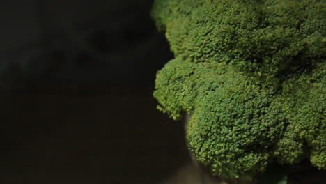 Pan-right-on-healthy-head-of-fresh-green-broccoli-vegetable-against-black-background