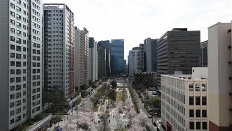 Aerial-drone-fly-over-Seoul-city-centre-skyscraper-towers-and-people,-South-Korea