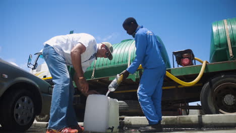 Männer-Füllen-Während-Einer-Krise-Behälter-Mit-Einem-Wasserwagen