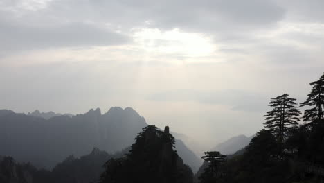 El-Valle-De-La-Montaña-Se-Revela-A-Través-De-Los-árboles,-Vista-Aérea-De-Los-Rayos-Del-Sol-Sobre-El-Paisaje-De-La-Ladera-De-La-Montaña.