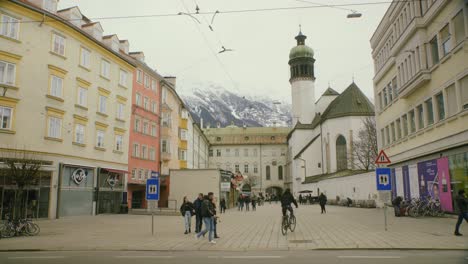 Polizeiauto-Verlässt-Innsbrucks-Stadtplatz,-Während-Fußgänger-Und-Radfahrer-Vorbeifahren