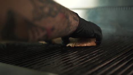 Hands-with-black-gloves-puts-burger-bread-on-hot-plate