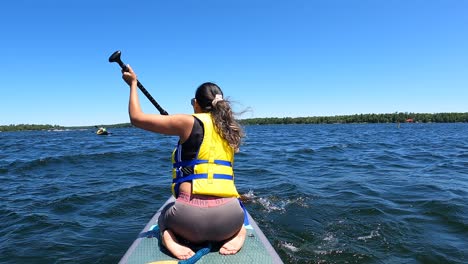 Chica-Haciendo-Paddleboard-Mientras-Está-Sentada-De-Rodillas.