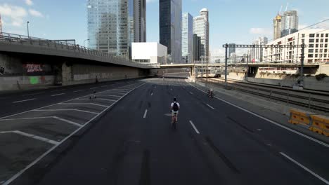 Aerial-drone-view-tracking-a-man-biking-on-a-quiet-road-in-Tel-Aviv,-Israel---lockdown