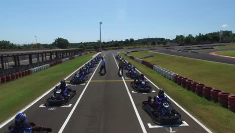 Aerial-drone-shot-of-kart-racers-lined-up-on-the-starting-line-waiting-for-the-race-to-start-with-tension-and-anxiety