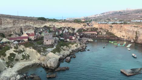 Bahía-Del-Ancla,-Parque-Inflable-De-Vuelo-Sobre-El-Mar-Y-Casas-Coloridas-En-El-Pueblo-De-Popeye