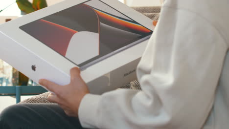 Person-at-home-holding-up-brand-new-Apple-M1-MacBook-Pro-box