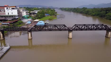 Toma-Aérea-De-Un-Dron-Acercándose-Al-Puente-Sobre-El-Río-Kwai,-Ferrocarril-De-La-Muerte-De-Tailandia,-Kanchanaburi,-Tailandia