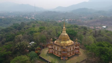 Aerial-view-of-a-golden-Buddhist-temple-on-a-hill-in-Luang-Prabang,-Laos