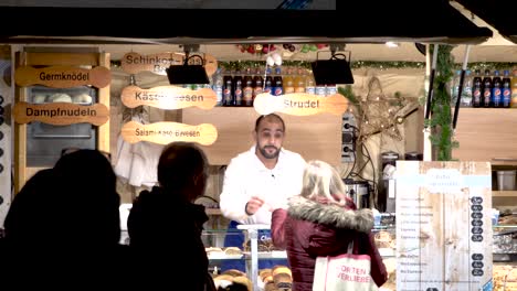 Woman-is-handing-over-cash-at-christmas-market-booth-to-man-in-downtown-munich-city