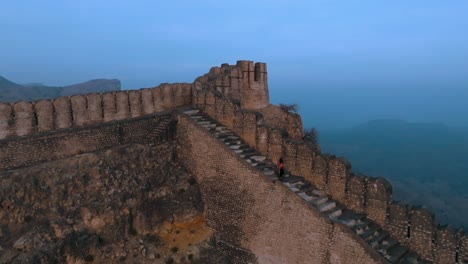 Drone-flight-at-ranikot-fort-in-sindh-pakistan---Man-walking-on-historical-ruin-wall