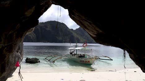 A-pump-boat-floating-on-the-turquoise-water-shot-from-inside-a-cave-at-El-Nido,-Palawan-Philippines