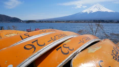 Vista-De-La-Montaña-Volcánica-Fuji-Con-El-Lago-Kawaguchi-Y-Un-Grupo-Naranja-De-Pequeñas-Canoas-Cerca-De-La-Orilla-En-El-Día-De-Cielo-Claro-De-Primavera---4k-Uhd-Video-Cortometraje