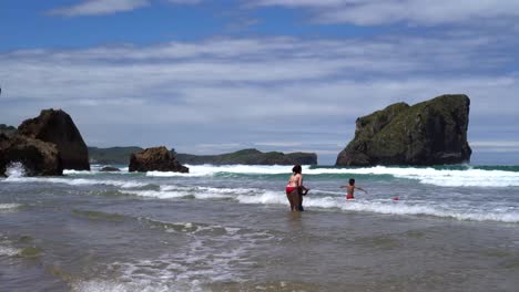 Family-Playing-Ball-Together-In-Ocean-Waves-At-Spanish-Beach,-Spain