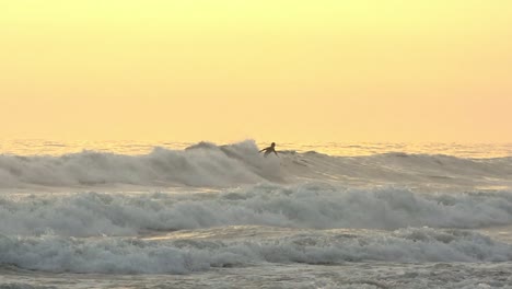 Surfista-Intentando-Una-Maniobra-Aérea-En-La-Hora-Dorada-Con-Una-Isla-Al-Fondo