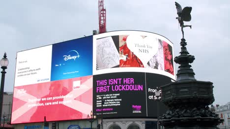 Lockdown-in-London,-slow-motion-pan-of-Sharftesbury-Memorial-Fountain-in-front-of-Piccadilly-Circus's-LED-signs-during-the-COVID-19-pandemic-2020