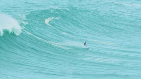 Jetskis-watch-as-wave-catches-up-to-surfer-at-Nazare,-tracking,-slow-mo