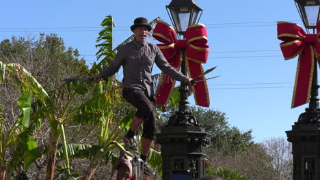 Street-performer-juggling-with-three-knifes-on-a-giraffe-unicycle