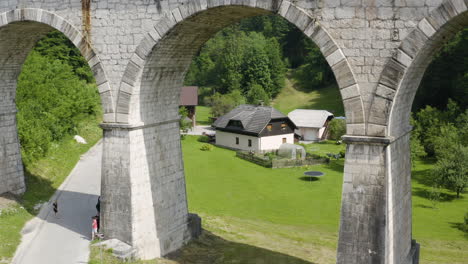 Low-aerial-push-in-through-the-old-railway-bridge-arch-in-rural-area-of-Ravne-na-Koroskem,-Slovenia