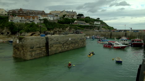 People-in-kayaks-canoes-and-fishing-boats-in-a-harbour-in-Cornwall