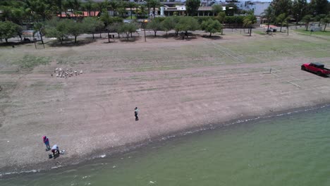 A-woman-carrying-a-child-on-the-shore-of-a-lake