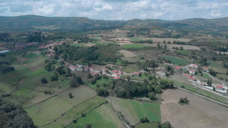 Toma-Panorámica-Aérea-De-Un-Pueblo-Remoto-En-El-Norte-De-Portugal-Con-Molinos-De-Viento-En-El-Fondo.