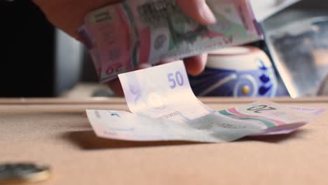 Hand-dropping-the-new-banknotes-of-the-Mexican-national-currency,-slow-motion