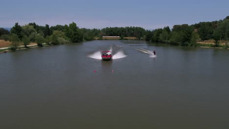 Powerful-speedboat-aerial-view-with-water-skier-surfing-behind-speeding-vessel-extreme-sports-boarding-fun