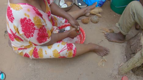 African-woman-sit-on-ground,-mash-coconut-in-mortar-for-powder-flour-or-starch