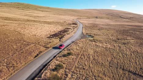 Toma-Aérea-Hacia-Atrás-Sobre-Los-Campos-Siguiendo-Un-Coche-Rojo.