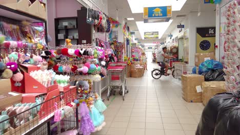 View-of-goods-inside-Chinese-business-center-in-Europe,-person-on-bike-passing,-Slow-motion-dolly