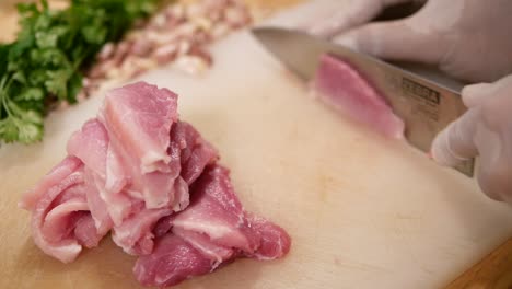 Hand-with-Glove-Use-Knife-to-Slice-Pork-Loin-into-Biting-Size-Pieces,-Close-Up