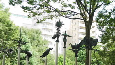 Statuen-Japanischer-Fabelwesen-Stehen-Inmitten-Der-Natur-In-Einem-Ruhigen-Tokioter-Park-Mit-Modernen-Wohnblöcken-Im-Hintergrund