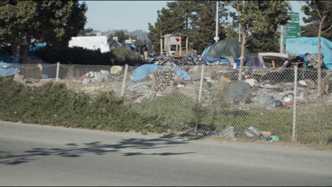 A-panning-wide-shot-of-a-homeless-camp-along-the-freeway-in-Berkeley,-California