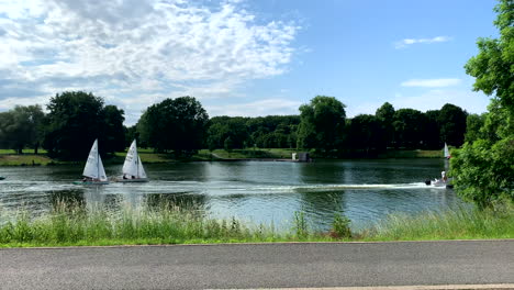 Dos-Veleros,-Una-Lancha-A-Motor-Y-Un-Bote-A-Pedales,-Recorren-El-Lago-Aasee-Al-Sol-En-Münster,-Alemania