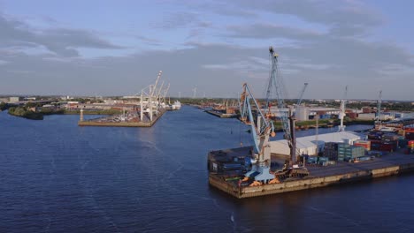 Drone-flight-over-Hamburg-harbour,-Germany-with-assorted-moored-vessels-at-the-wharfs-and-cranes-at-the-container-depot