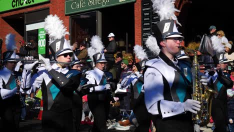 Marching-Band-with-feather-hats-playing-music-on-trombones-and-flutes-while-walking-down-the-main-street-during-the-Thanksgiving-Parade-2019-in-Plymouth-Massachusetts