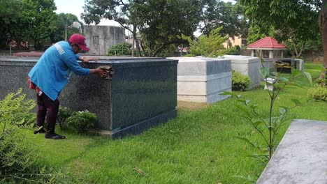 Cemetery-caretaker-cleans-graveyard-tombs-inside-manila-memorial-park-in-manila,-Philippines