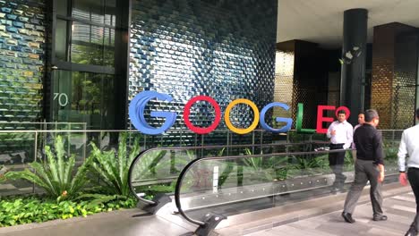 La-Gente-Caminando-Pasa-Por-Los-Carteles-De-Google-En-La-Planta-Baja-De-La-Oficina-De-Google-En-Singapur.